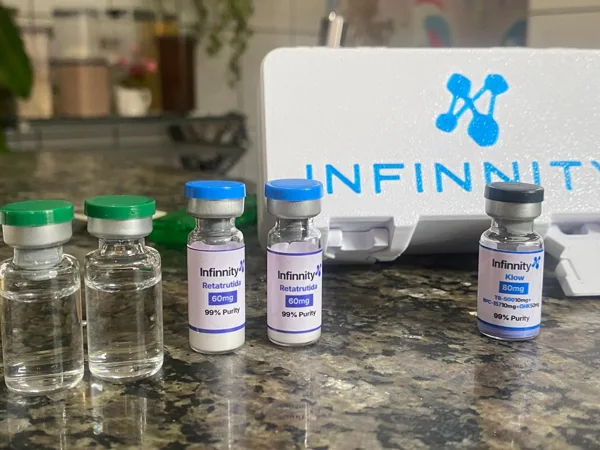 Frascos de Klow 80 mg e Retatrutida 60 mg diante de uma embalagem Infinnity.